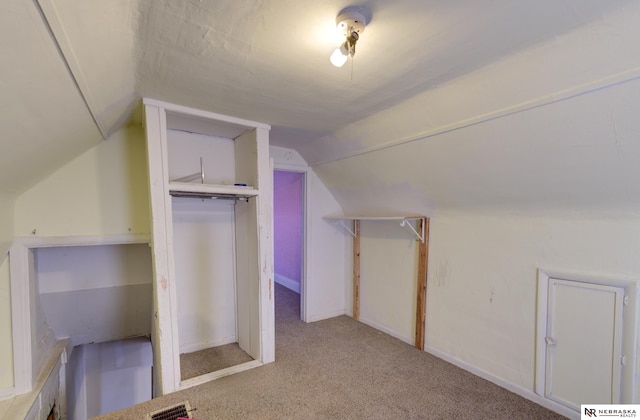 bonus room with vaulted ceiling and light carpet