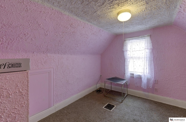 additional living space featuring vaulted ceiling and a textured ceiling