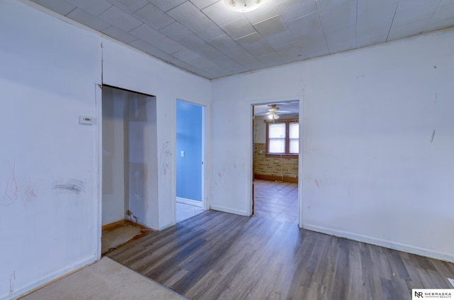 unfurnished room featuring hardwood / wood-style flooring and brick wall