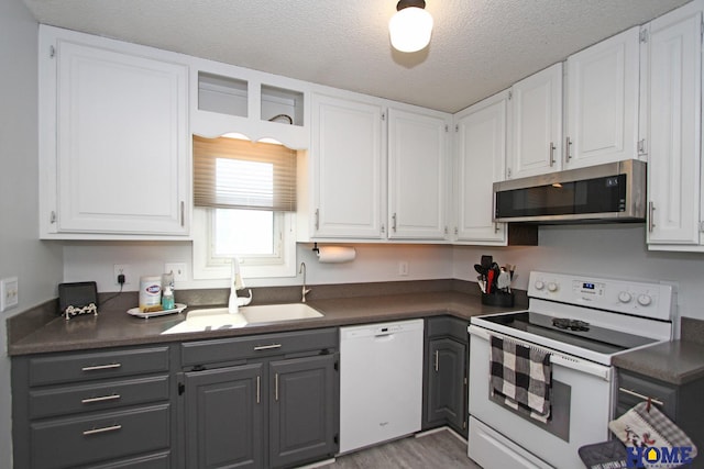 kitchen featuring sink, white cabinets, and white appliances