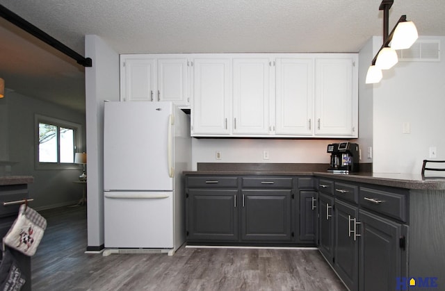 kitchen with white refrigerator, dark hardwood / wood-style floors, a textured ceiling, and white cabinets