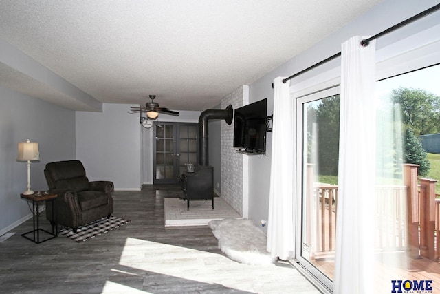 interior space with dark hardwood / wood-style flooring, a wood stove, ceiling fan, and a textured ceiling