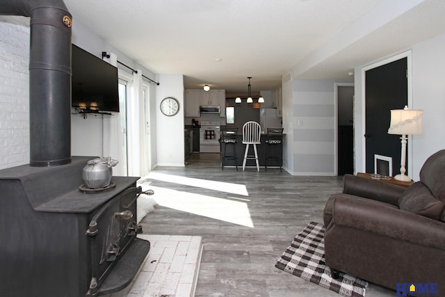 living room featuring wood-type flooring, a barn door, and a wood stove