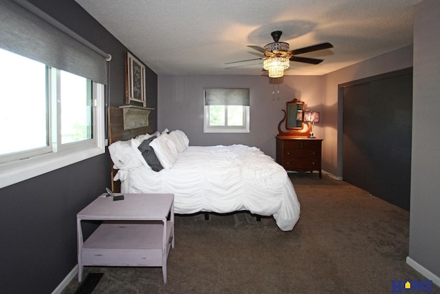 bedroom with ceiling fan, dark carpet, and multiple windows