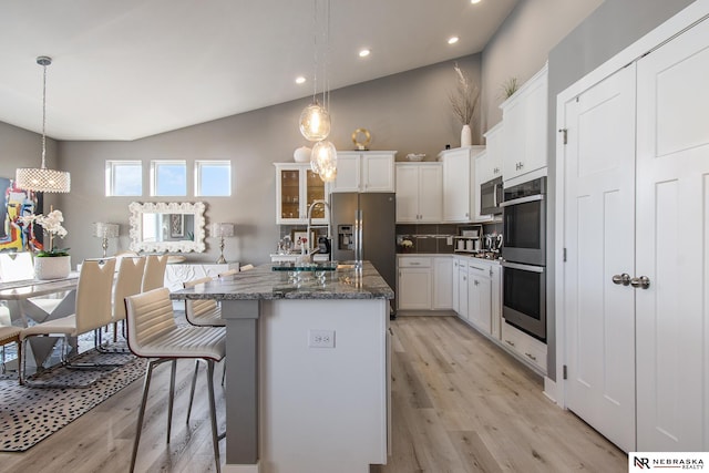 kitchen with a kitchen island with sink, sink, decorative light fixtures, and stainless steel appliances