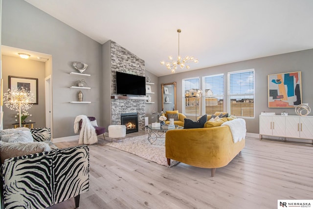 living room featuring a notable chandelier, a stone fireplace, high vaulted ceiling, and light wood-type flooring