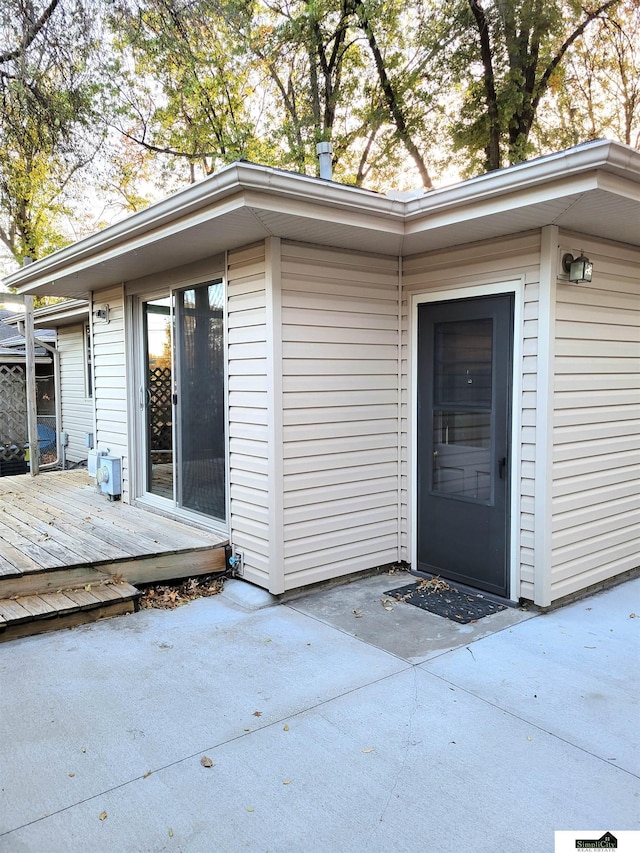 entrance to property featuring a wooden deck and a patio