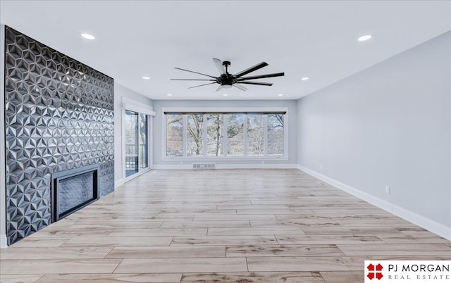 unfurnished living room with ceiling fan, a fireplace, and light hardwood / wood-style floors