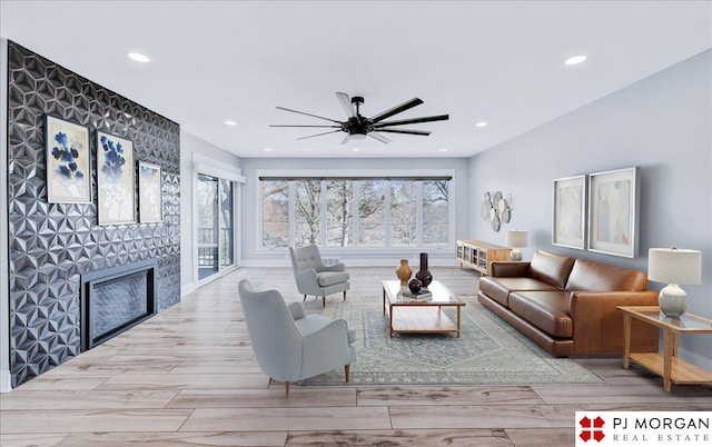 living room with ceiling fan, a fireplace, and light wood-type flooring