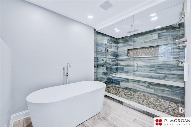 bathroom featuring plus walk in shower and hardwood / wood-style floors