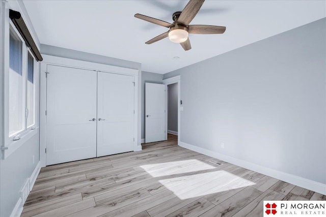 unfurnished bedroom featuring light hardwood / wood-style flooring, ceiling fan, and a closet