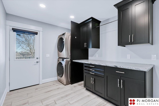 washroom featuring cabinets, stacked washing maching and dryer, and light hardwood / wood-style floors