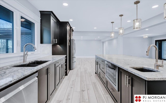 kitchen with tasteful backsplash, appliances with stainless steel finishes, sink, and decorative light fixtures