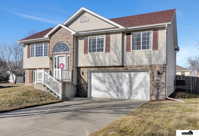 bi-level home featuring a garage and a front lawn