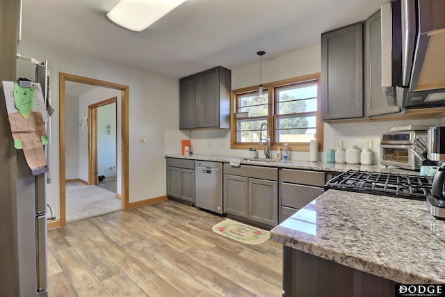 kitchen featuring light stone counters, sink, pendant lighting, and stainless steel dishwasher