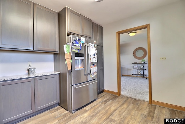 kitchen with high end fridge, light stone counters, and light hardwood / wood-style flooring