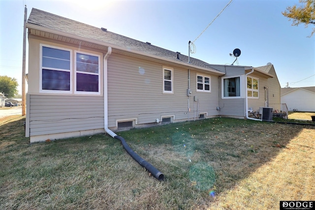 rear view of property featuring central air condition unit and a lawn