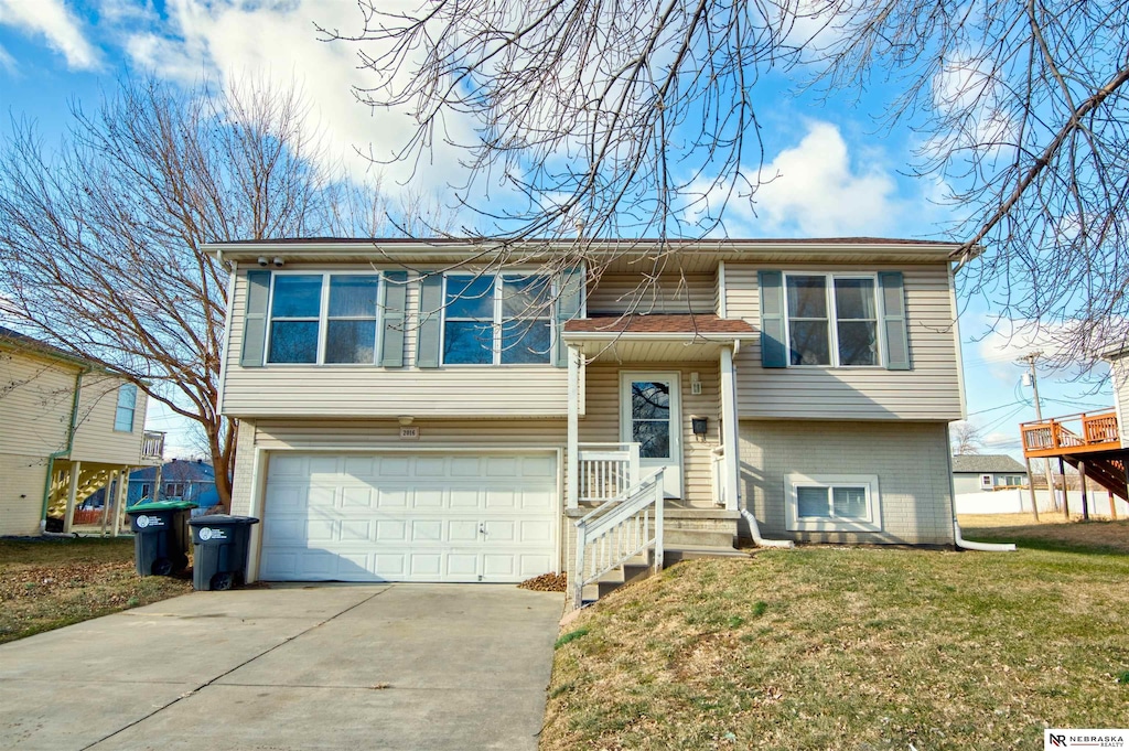 bi-level home featuring a garage and a front lawn