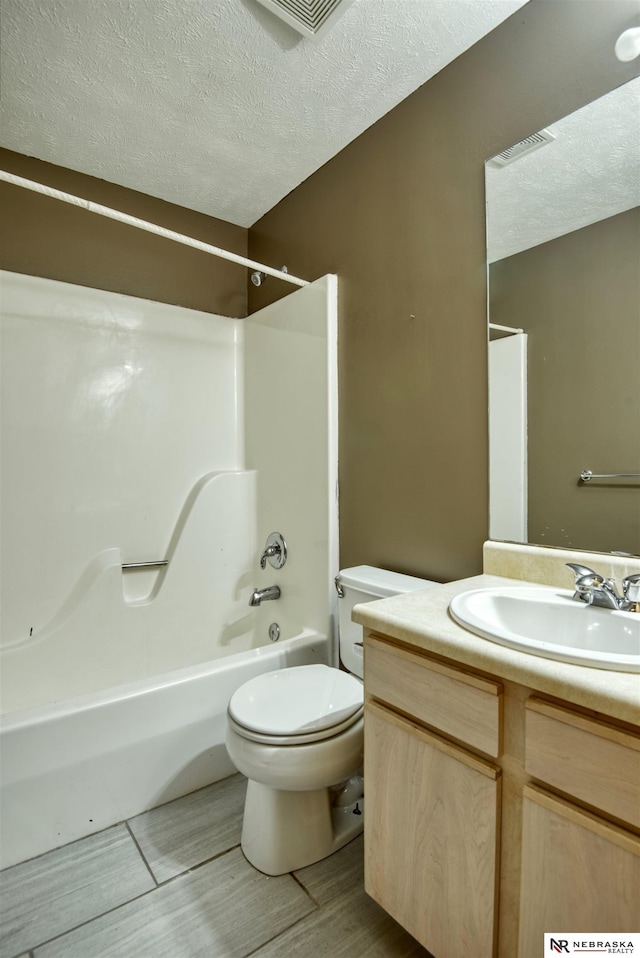 full bathroom featuring vanity, toilet, a textured ceiling, and shower / bath combination