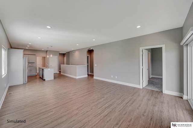 unfurnished living room featuring sink and light wood-type flooring