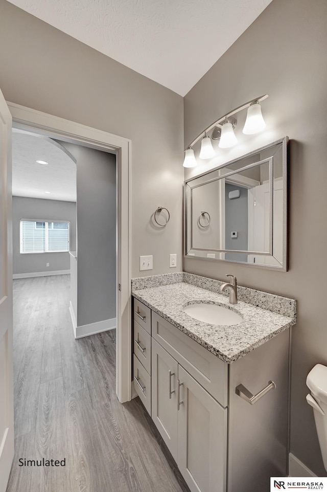 bathroom with wood-type flooring, vanity, and toilet