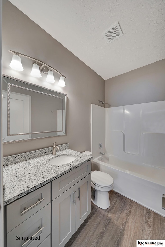 full bathroom featuring shower / bath combination, hardwood / wood-style floors, vanity, a textured ceiling, and toilet