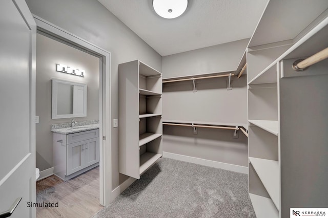 walk in closet featuring light colored carpet and sink