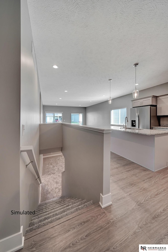 staircase with sink, a wealth of natural light, and a textured ceiling