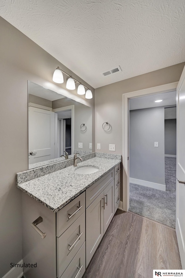 bathroom with vanity, hardwood / wood-style flooring, and a textured ceiling