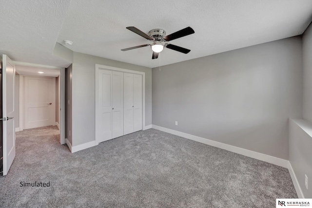 unfurnished bedroom featuring ceiling fan, light colored carpet, a closet, and a textured ceiling