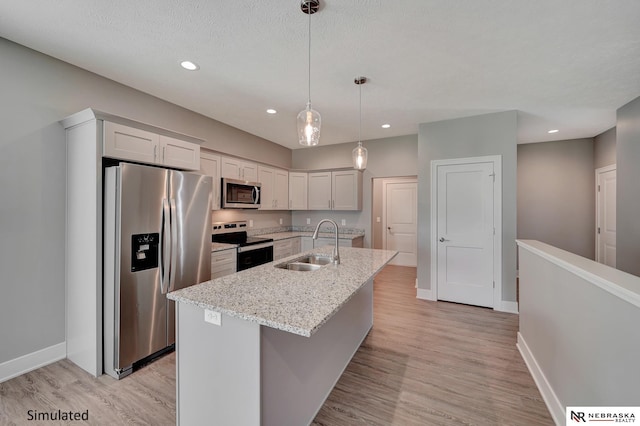 kitchen featuring sink, hanging light fixtures, stainless steel appliances, light stone countertops, and a center island with sink