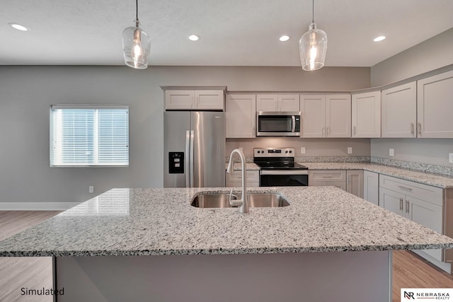 kitchen featuring pendant lighting, appliances with stainless steel finishes, sink, and a center island with sink