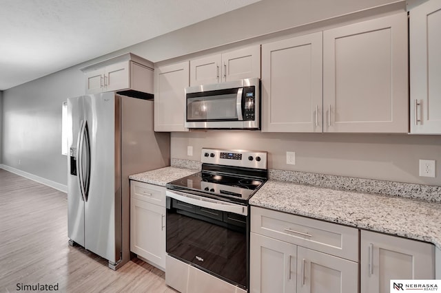 kitchen featuring light hardwood / wood-style flooring, light stone countertops, white cabinets, and appliances with stainless steel finishes