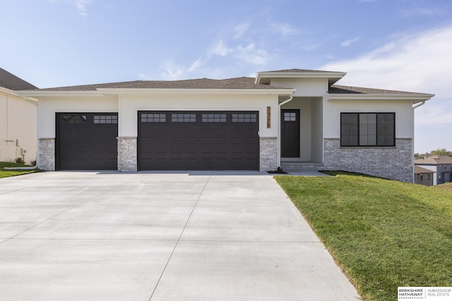 prairie-style house featuring a garage and a front lawn