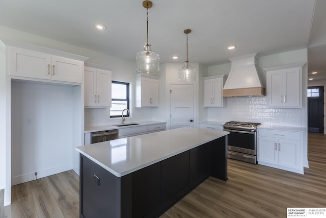 kitchen featuring premium range hood, a center island, white cabinets, and appliances with stainless steel finishes