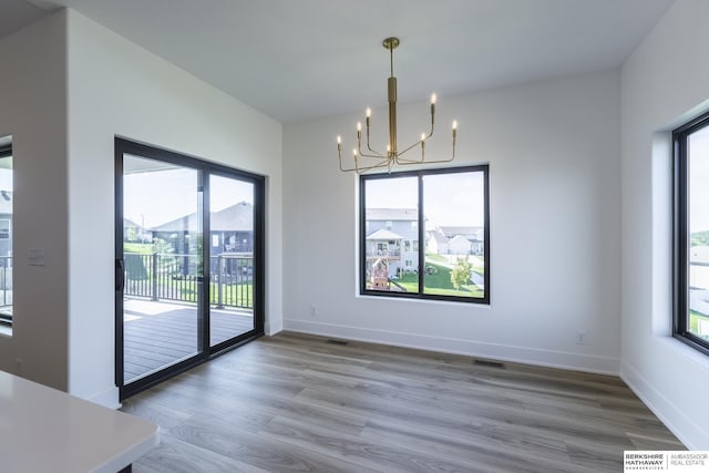 unfurnished dining area with hardwood / wood-style flooring and a chandelier