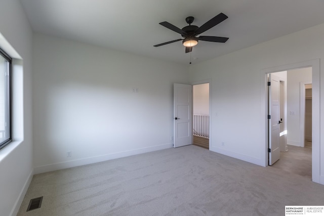 unfurnished bedroom with ceiling fan, a spacious closet, and light carpet