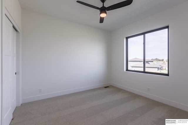 carpeted spare room featuring ceiling fan