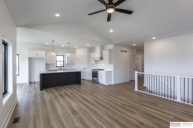 kitchen featuring custom exhaust hood, white cabinetry, a kitchen island, and stainless steel range oven