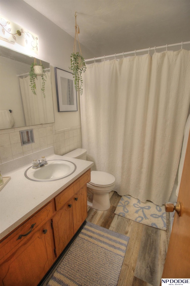 bathroom featuring wood-type flooring, toilet, vanity, and backsplash