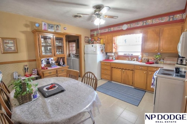 kitchen featuring ceiling fan, washer and clothes dryer, sink, and white appliances