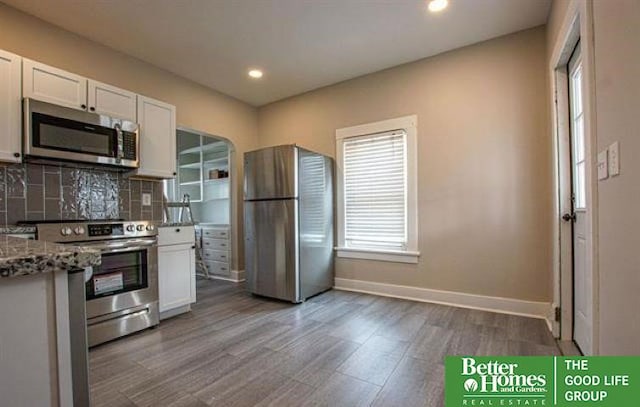 kitchen featuring stone counters, appliances with stainless steel finishes, tasteful backsplash, white cabinetry, and wood-type flooring