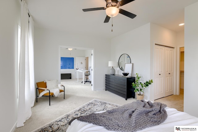 bedroom with light colored carpet, ceiling fan, and a closet