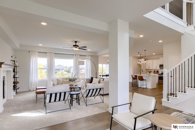 living room with a wealth of natural light, ceiling fan, and light hardwood / wood-style flooring