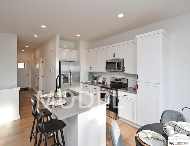 14803 Willow St, Bennington, NE 68007 - kitchen featuring stainless steel appliances, a sink, light wood finished floors, a kitchen bar, and recessed lighting