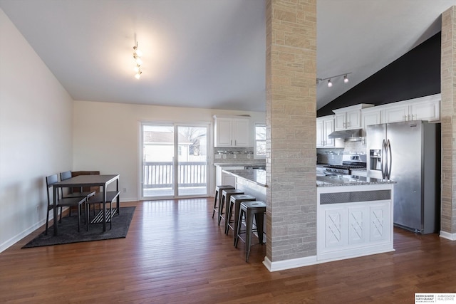 kitchen with appliances with stainless steel finishes, dark hardwood / wood-style floors, white cabinetry, a kitchen bar, and light stone countertops