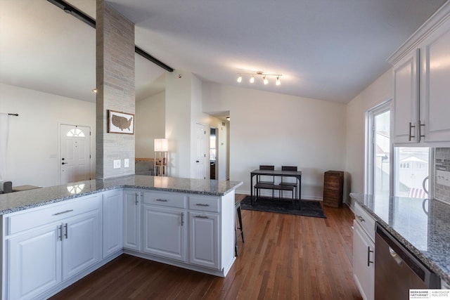 kitchen featuring dishwasher, lofted ceiling, white cabinets, and kitchen peninsula