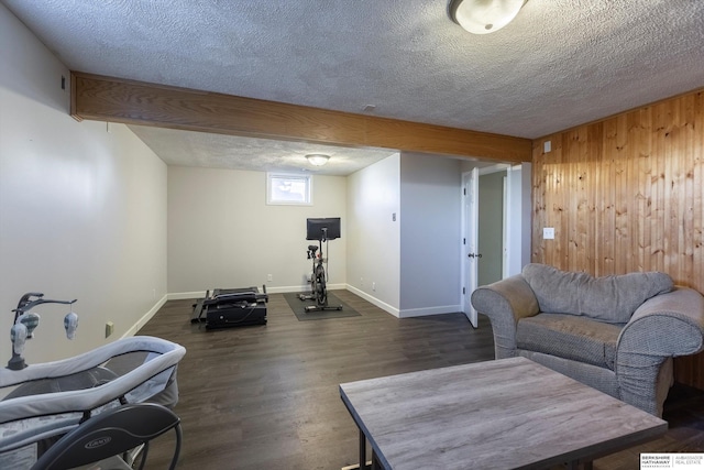 living room with dark wood-type flooring, wooden walls, and a textured ceiling