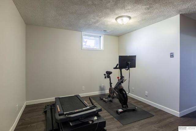 exercise area featuring dark wood-type flooring and a textured ceiling