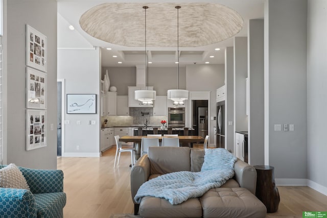 living room with a towering ceiling and light wood-type flooring